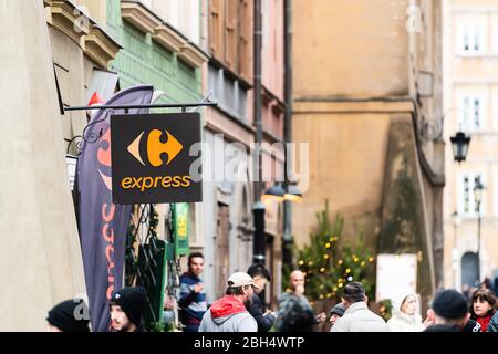 Warsaw, Poland - December 25, 2019: Carrefour express convenience grocery store shop sign in historic old town by market square with people walking by Stock Photo