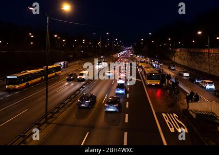 Warsaw, Poland - December 20, 2019: Above high angle aerial view of Aleja Armii Ludowej street avenue in Warszawa at night with traffic cars, bus stop Stock Photo