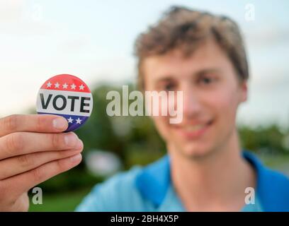 Smiling man holding vote button Stock Photo