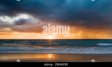 Beach under dramatic sky at sunset Stock Photo