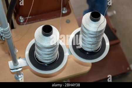 A top down view of two spools of thread on a leather sewing machine. Bokeh effect. Stock Photo