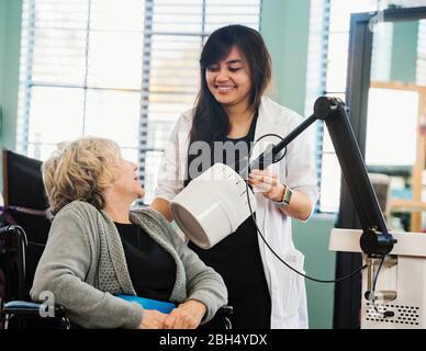 Smiling doctor holding machine by senior woman Stock Photo