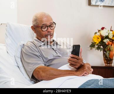 Senior man using smart phone in bed Stock Photo