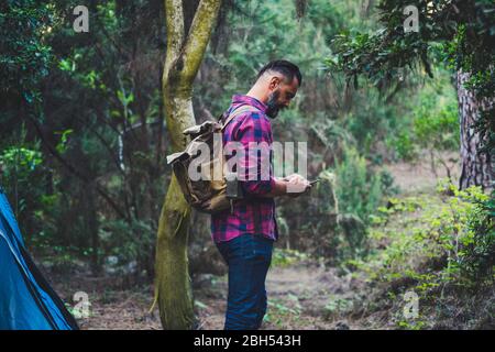 Man wearing backpack using smart phone in forest Stock Photo