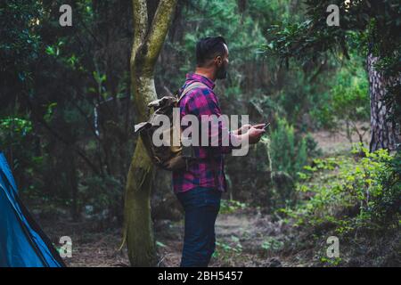 Man wearing backpack using smart phone in forest Stock Photo