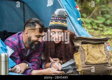 Smiling couple lying in tent using tablet Stock Photo