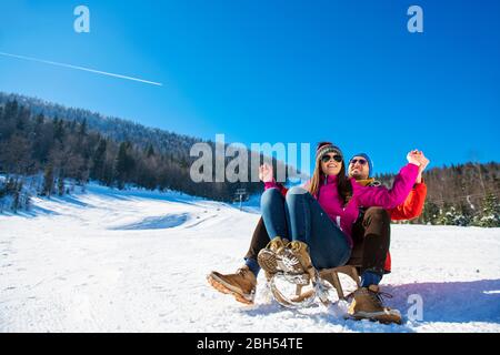 Young happy couple sledding in winter at ski center Stock Photo