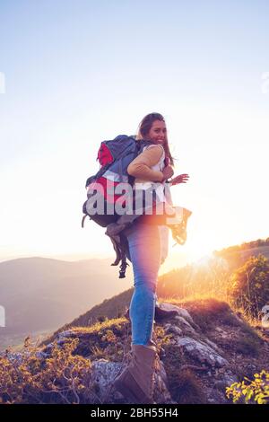 Hikers with backpacks relaxing on top of a mountain and enjoying the view of valley Stock Photo