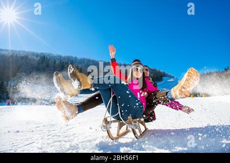 Young happy couple sledding in winter at ski center Stock Photo