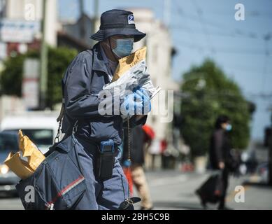 San Francisco, United States. 23rd Apr, 2020. A USPS letter carrier, masked and gloved against the coronavirus, crosses Stockton Street tin San Francisco on Thursday, April 23, 2020. Photo by Terry Schmitt/UPI Credit: UPI/Alamy Live News Stock Photo