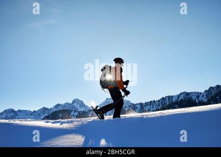 Man in silhouette skiing on fresh powder snow at the mountains against sunny sky near Almaty, Kazakhstan Stock Photo