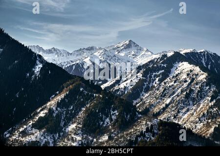 High mountains with snow and pine trees and peak against blue sky in Kazakhstan at winter time Stock Photo