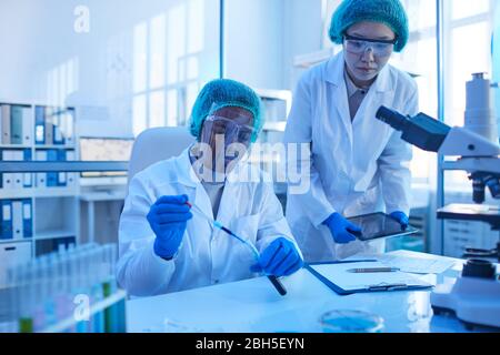 Two scientists working in team at the table they examining samples in test tubes Stock Photo