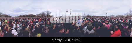 Large crowd of Donald Trump supporters listening to inaugural speech as President Elect takes the oath of allegiance during his swearing-in ceremony at National Mall. An estimated 300,000 to 600,000 people attended the public ceremony held on Friday, January 20, 2017 at the West Front of the United States Capitol in Washington DC for 58th Presidential Inauguration. Stock Photo