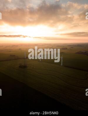 aerial landscape view of fields in the sunset with big white windmills on Stock Photo