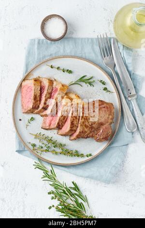 Keto ketogenic diet beef steak, striploin on gray plate on white background. Paleo food recipe Stock Photo