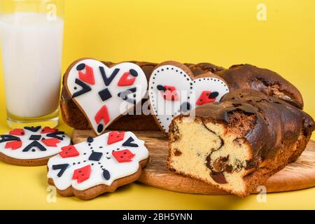 Slices of Romanian sponge cake with red traditional towel with manual stitch on wooden board, Easter painted eggs and home made ginger bread hearts, A Stock Photo