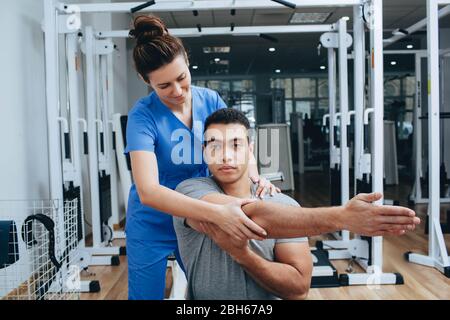 Physiotherapist helps to treatment a hand joint for the mixed race patient. Physiotherapy, joint treatment in a sport health center Stock Photo