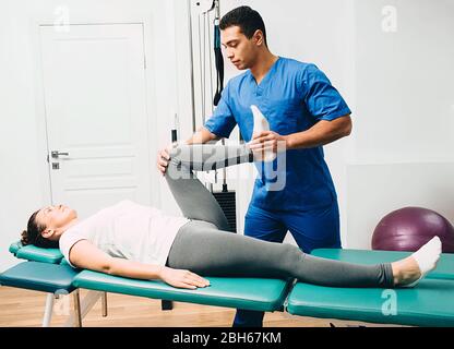physiotherapist doing leg muscle stretching to the patient. Treatment of a woman's sciatic nerve Stock Photo