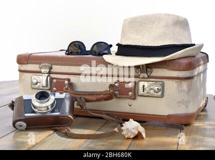retro suitcase and cameron punt on a wooden table with straw hat and glasses on white background Stock Photo