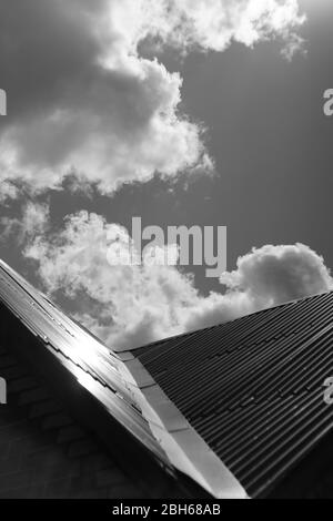 Roof made of stainless steel against the sunny cloudy sky, bw photo. Stock Photo