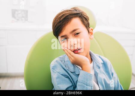 little boy with teeth pain, he is sad and upset.He setting and dentist chair ad dental clinic Stock Photo