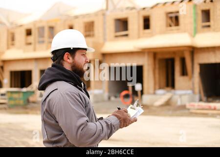 European builder drawing plan in notebook at construction site. Stock Photo