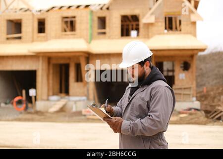 Architect drawing plan in notebook at construction site. Stock Photo