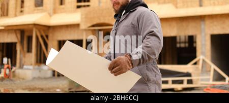 Banner of foreman holding architecture drawing plan on paper at construction site. Stock Photo