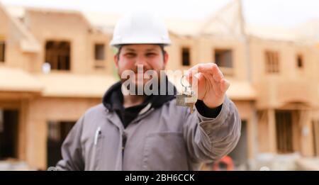 Banner, focus on apartment keys, foreman giving and wearing hardhat. Stock Photo