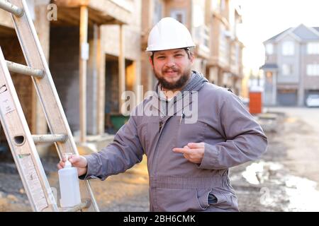 Young foreman using disinfectant soap on construction site. Stock Photo