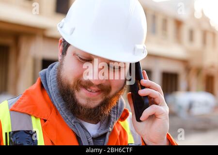 Portrait of engineer talking by smartphone on construction site. Stock Photo
