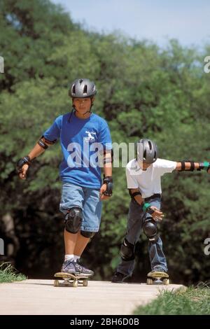 Austin Texas USA: 12-year-old Hispanic, Asian boys on skateboards wearing helmets and safety gear. ©Bob Daemmrich Stock Photo