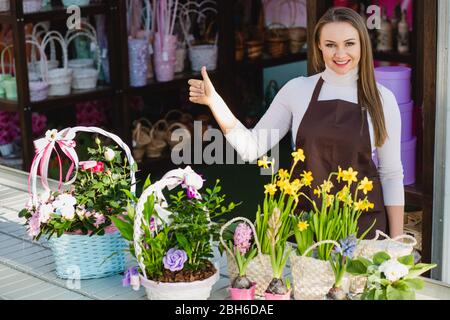 owner of a flower shop shows his hand symbol of cool and looks smiling at the camera. Stock Photo