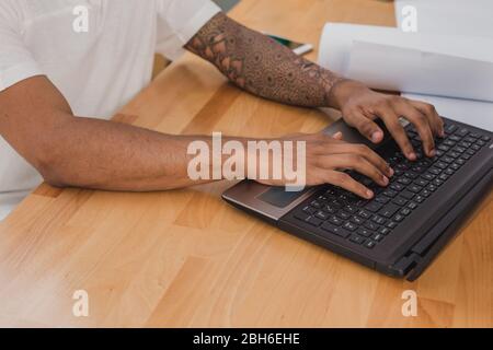 Men's hands with tattoo closeup, typing on laptop keyboard. Stock Photo