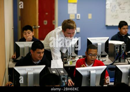 Dallas, Texas, January 23, 2009: Teacher leans in with seventh and eighth grade students in the computer lab at Peak Preparatory Academy in east Dallas. The school is a public charter school that has shown remarkable growth in student achievement in its five-year history. ©Bob Daemmrich Stock Photo
