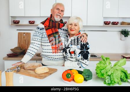 elderly couple embracing in the kitchen, seniors people spending time together at home. Stock Photo