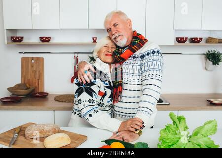 elderly couple embracing in the kitchen, seniors people spending time together at home. Stock Photo