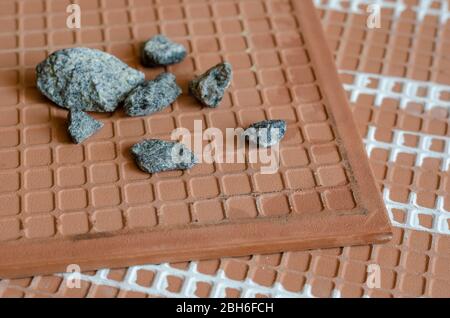 Ceramic tiles and crushed stone close-up. A detailed shot of a group of rubble stones on the back of a ceramic tile. Building materials. Selective foc Stock Photo