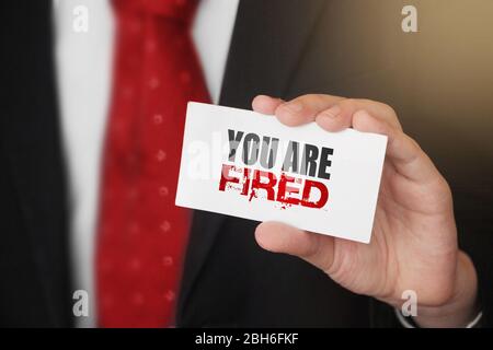 You are fired message on business card shown by a businessman. Labour force crisis Business risk management concept Stock Photo