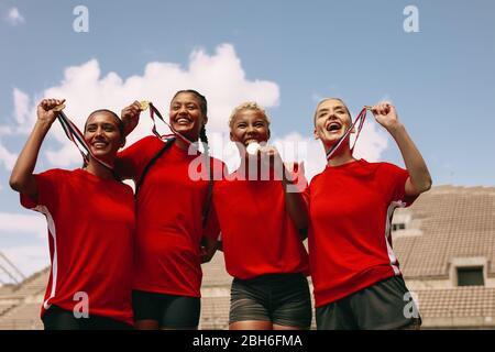 Female soccer players with medals after winning the championship. Woman football team celebrating the victory at stadium. Stock Photo