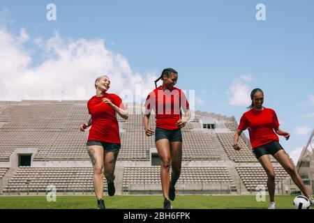 Group of female football players training on soccer field. Young woman soccer players practicing ball control during training session. Stock Photo
