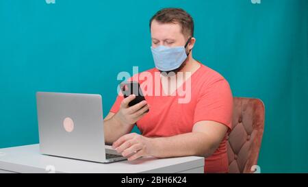 Man working from home. Using a smartphone. Bearded man in a protective mask works at home. Stock Photo