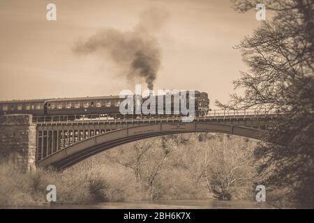 Vintage UK steam train puffing across Victoria Bridge & River Severn in Worcestershire on Severn Valley Railway heritage line. Stock Photo