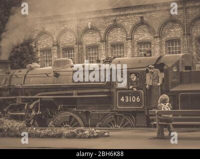 Sepia view of vintage UK steam train 43106 arriving at Kidderminster station, Severn Valley Railway heritage line, isolated trainspotter watching. Stock Photo