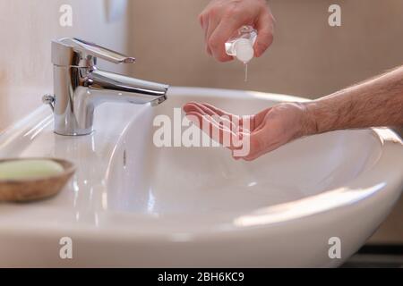 Young caucasian man applying antibacterial alcohol gel on hands from a small portable bottle. Disinfecting hands with hand sanitizer to prevent corona Stock Photo