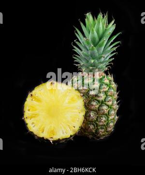 Fresh pineapple isolated on black background. Juicy pineapple. Fruits photo collection. One and half pineapple isolated on black background. Stock Photo