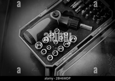 Screwdriver with a set of bits. Used bit set for screwdriver in plastic box. Hand tools in the household. View from above. Selective focus. Stock Photo