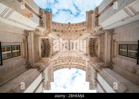 Detail of Rua Augusta triumphal Arch in the historic center of the city of Lisbon in Portugal. Blue sky with clouds. Perspective from the road.