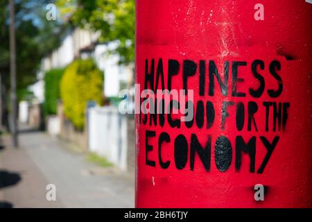 London / UK - 21 April 2020: "Happiness is no good for the economy". Local artwork on a postbox in Honor Oak. Stock Photo